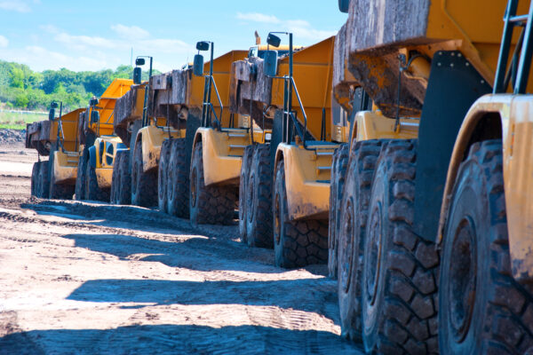 Row of dump trucks driving through construction zone