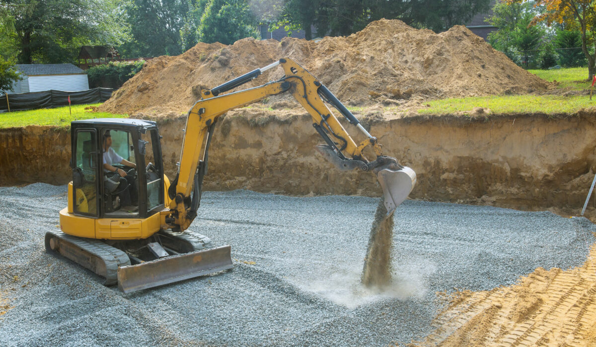 Excavator filling in holes with gravel