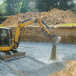 Excavator filling in holes with gravel