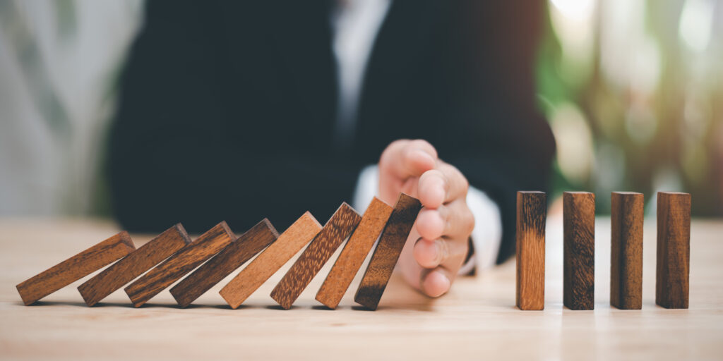 Human hands blocking wooden dominos