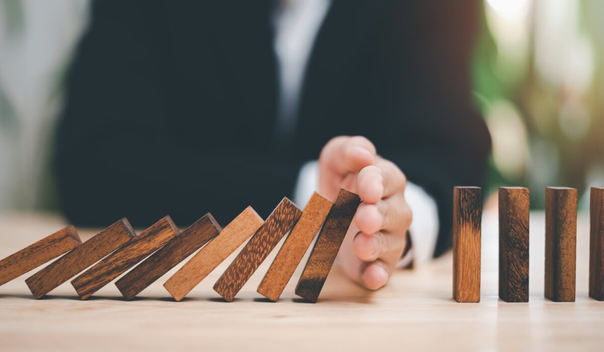 Human hands blocking wooden dominos