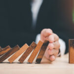 Human hands blocking wooden dominos