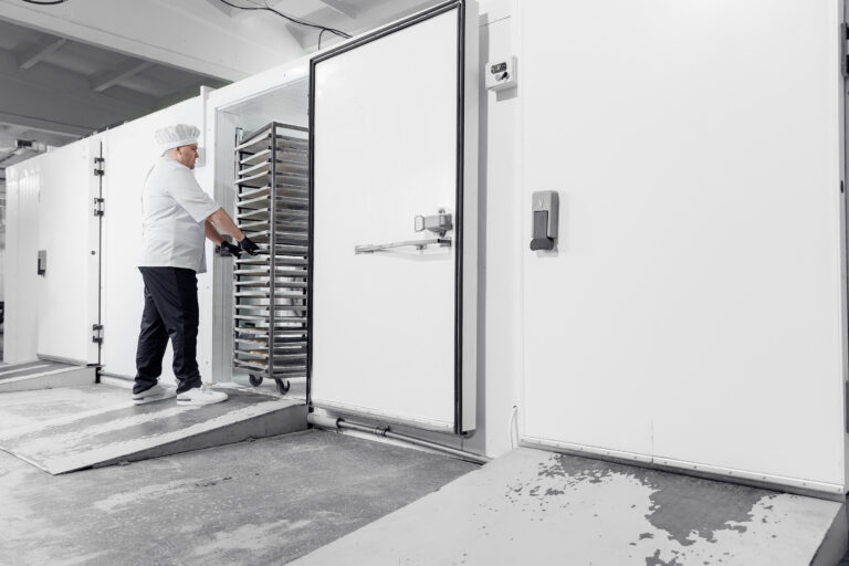 Male caucasian adult technologist freezing puff pastry in industrial confectionery production line.