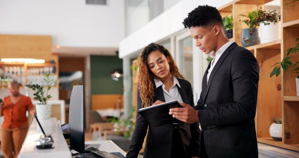 Reception, employees and tablet with teamwork, hotel and accommodation with cooperation.
