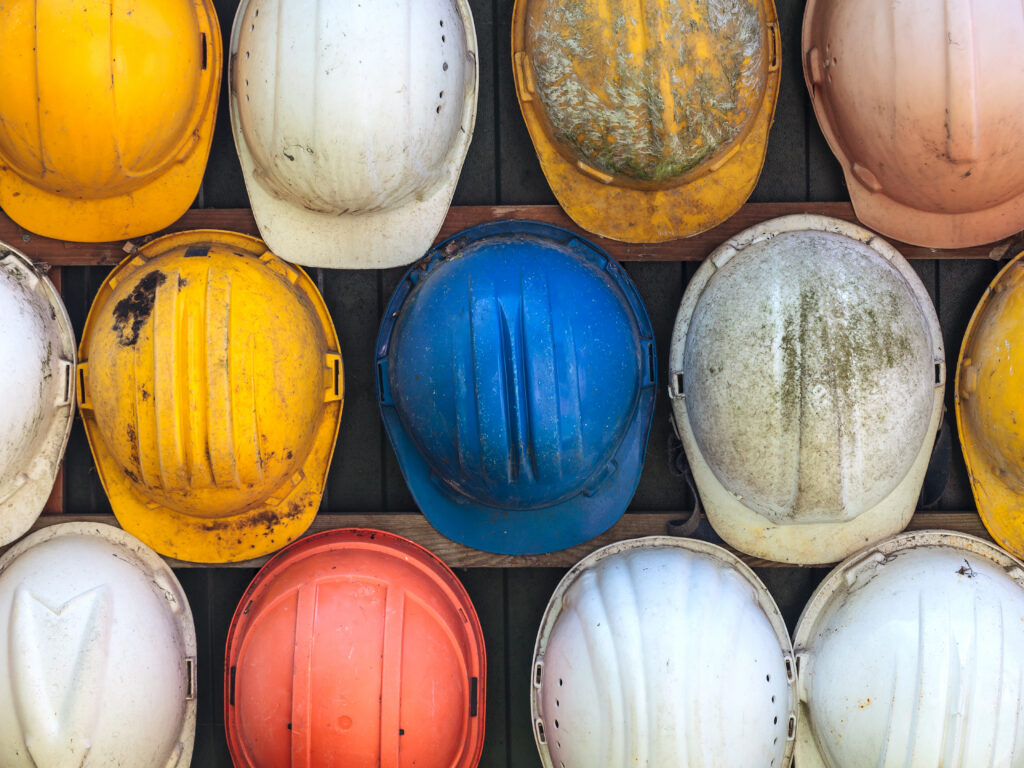 old used construction helmets on a wall