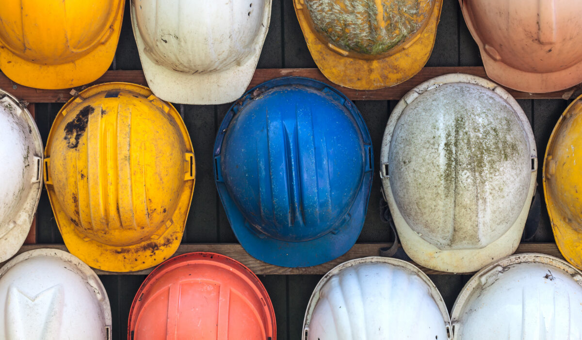 old used construction helmets on a wall