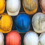 old used construction helmets on a wall