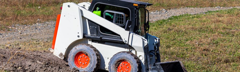 White mini loader working in rural area